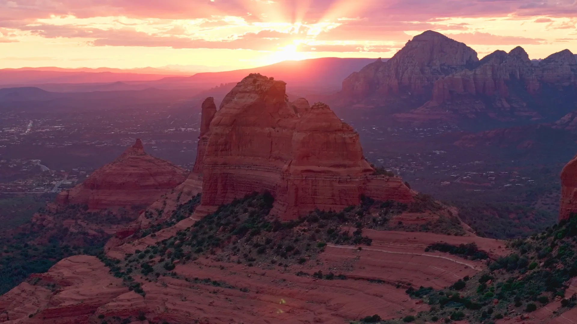Aerial view of Sedona's red rock formations at sunset, with the town below