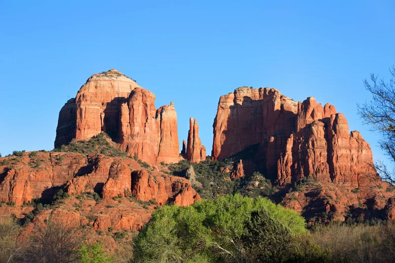 Cathedral Rock rising above evergreen forest under a clear Sedona sky